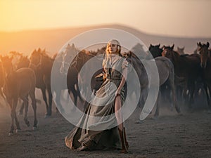 Woman in traditional Indian western dress on the background of herd of horses