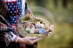 Woman in traditional Lithuanian outfit is holding Easter eggs