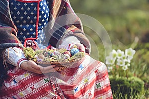 Woman in traditional Lithuanian outfit is holding Easter eggs