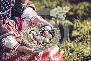 Woman in traditional Lithuanian outfit is holding Easter eggs