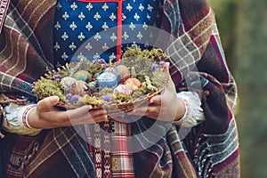 Woman in traditional Lithuanian outfit is holding Easter eggs