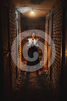 A woman in traditional Ukrainian clothing stands in a dark basement with a candle in her hands. The concept of a tragedy in