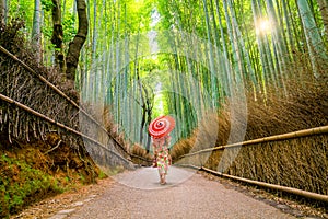 Woman in traditional Yukata with red umbrella at bamboo forest o