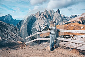 Woman on the trail is looking on majestic mountains at sunset