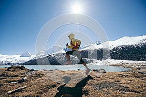 Woman trail runner cross country running in winter mountains