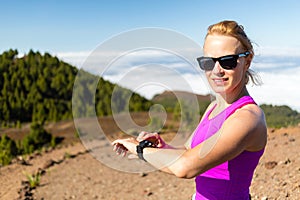 Woman trail runner looking at sport watch