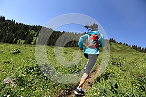 Woman trail runner running on beautiful mountain peak