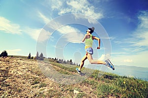 Woman trail runner running on beautiful mountain peak