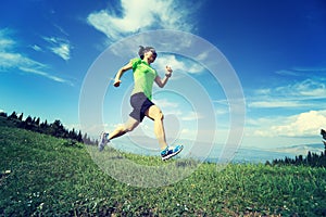 Woman trail runner running on beautiful mountain peak