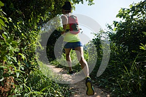 Woman trail runner running in sunny forest