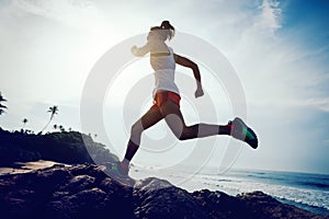 woman trail runner running to rocky mountain top