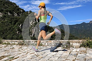 Woman trail runner running on top of mountain