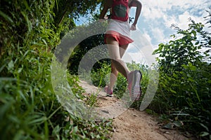 Woman trail runner running on tropical forest trail