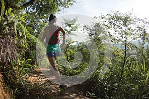 Woman trail runner running on tropical forest trail