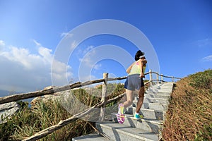 Woman trail runner running up on mountain stairs
