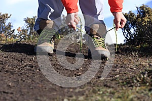 Woman trail runner tying shoelace on mountain peak