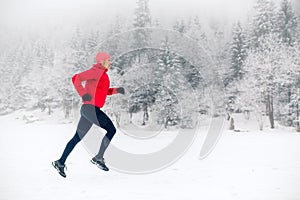 Woman trail running on snow in winter mountains