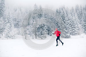 Woman trail running on snow in winter mountains