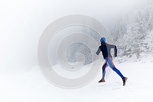 Woman trail running on snow in winter mountains