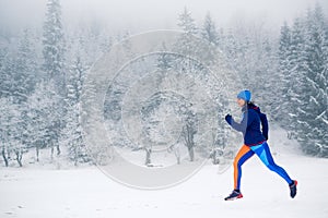 Woman trail running on snow in winter mountains