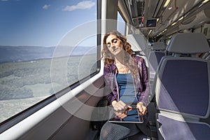 Woman in train sleeping with digital tablet in hands