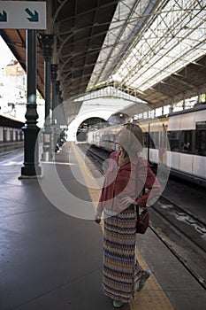 A woman at the train station waiting for the train to arrive.
