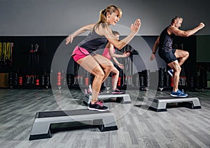 Woman trainer doing aerobic class with steppers in