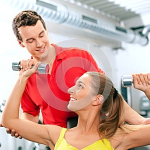 Woman with trainer and dumbbells in gym