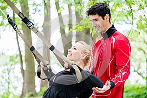 Woman with trainer at sling training