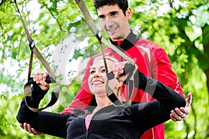 Woman with trainer at sling training