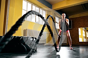 Woman training with battle ropes in gym