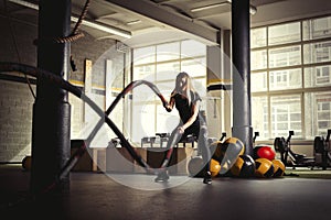 Woman training with battle ropes in gym