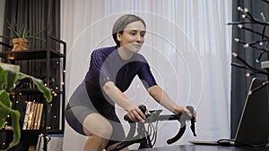 Woman is training indoor on smart bike trainer. Female is cycling on bicycle simulator