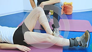 A woman is training leg`s muscles after injury in clinic