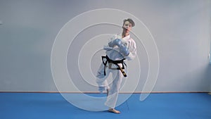 Woman training taekwondo tricks in gym. Female white kimono demonstrates karate technique. Martial art concept