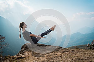 Woman training yoga on mountain cliff