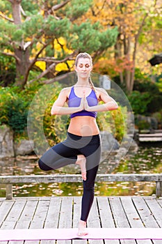 Woman training yoga outdoor in autumn Park