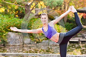 Woman training yoga outdoor in autumn park