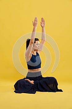 Woman training yoga pose with gazed up hands indoors.