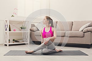 Woman training yoga in twisting sage pose.