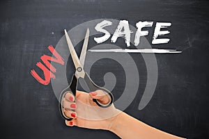 Woman transforming the word â€œunsafeâ€ into â€œsafeâ€ with scissors