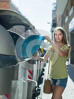Woman with trash bags near garbage bin