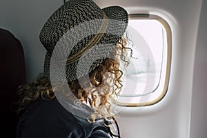 Woman travel on aircraft flight - fly for business or holiday vacation people inside airplane looking outside from the window -