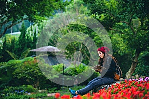 Woman travel nature in the flower garden. relax sitting on rocks and reading books In the midst of nature at national park doi