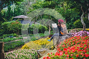 Woman travel nature in the flower garden. relax sitting on rocks and reading books In the midst of nature at national park doi