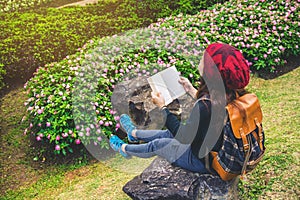 Woman travel nature in the flower garden. relax sitting on rocks and reading books In the midst of nature at national park doi