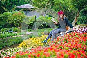 Woman travel nature in the flower garden. relax sitting on rocks and reading books In the midst of nature at national park doi