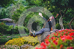 Woman travel nature in the flower garden. relax sitting on rocks and reading books In the midst of nature at national park doi