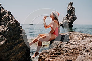 Woman travel sea. Happy tourist enjoy taking picture on the beach for memories. Woman traveler in Santa hat looks at