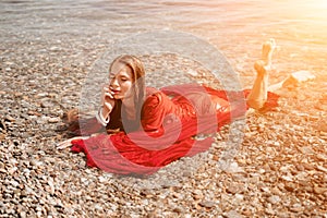 Woman travel sea. Happy tourist in red dress enjoy taking picture outdoors for memories. Woman traveler posing in sea